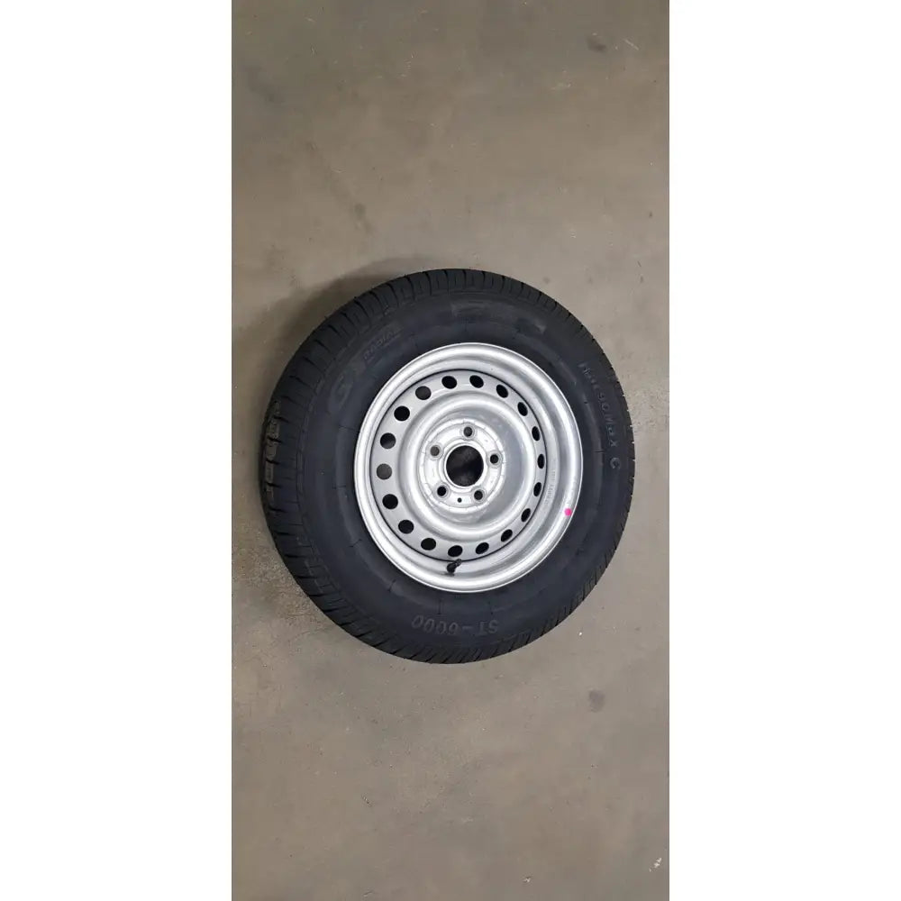Black rubber tire mounted on silver steel gaupen komp wheel r14c m+s with multiple circular holes
